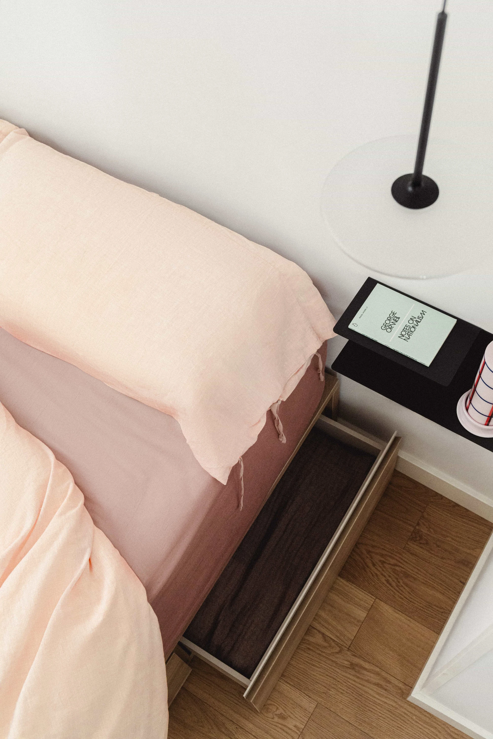 Detalle de dormitorio: cama con cajón de almacenaje y mesita de noche flotante negra.