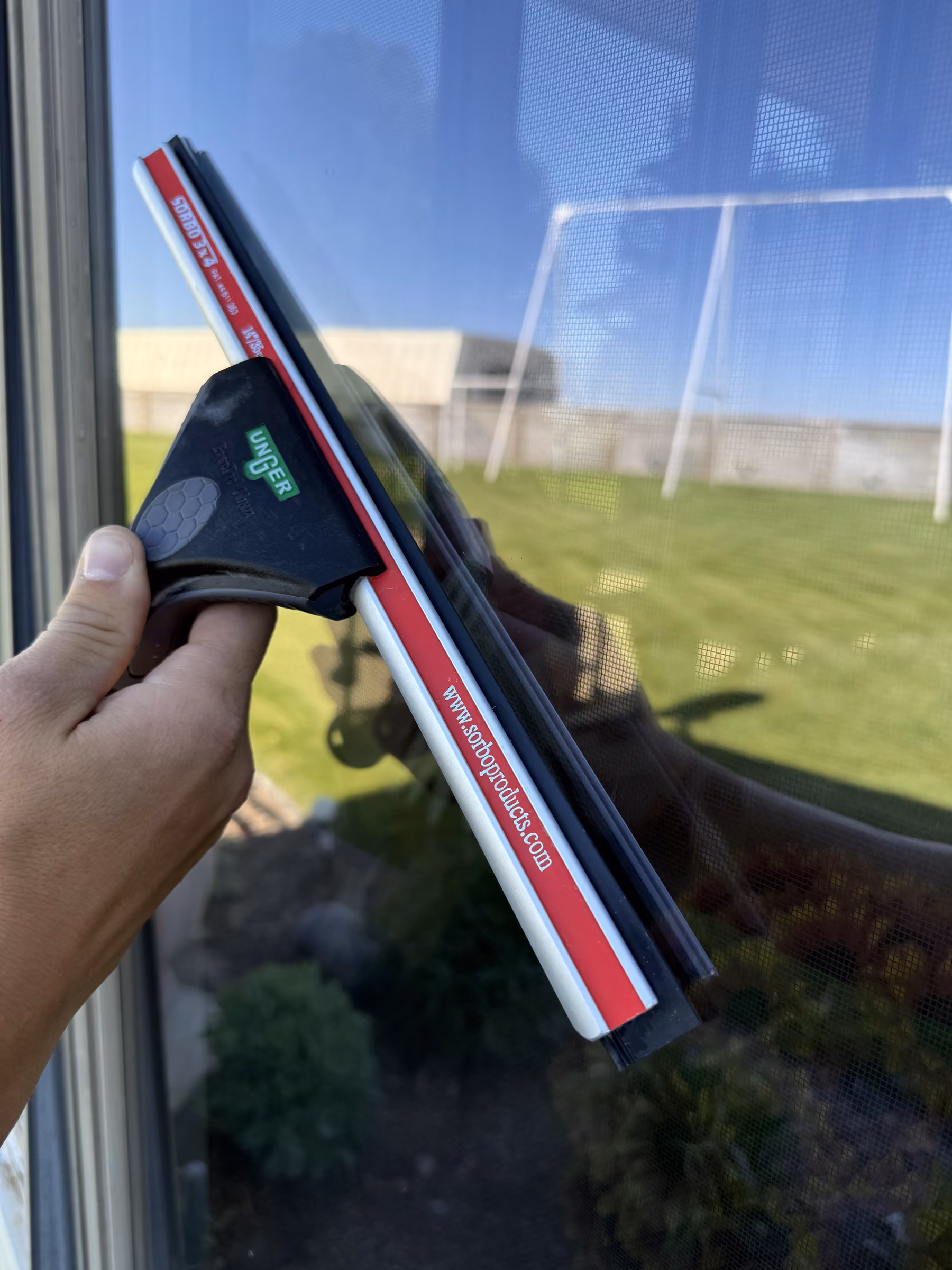 Close-up of a squeegee leaving streak-free glass on a Southeast Idaho home window