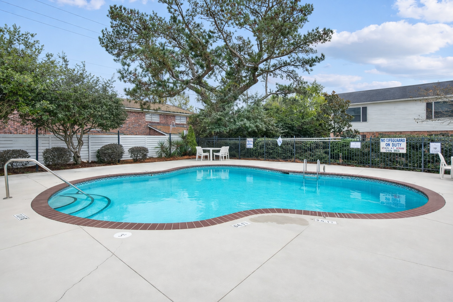 Swimming pool with white table and chairs in the background