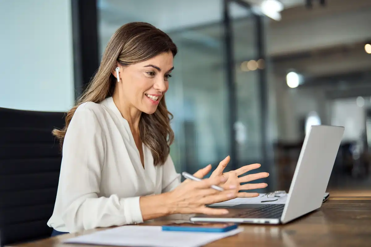 Smiling professional on a video call at her laptop in a modern office