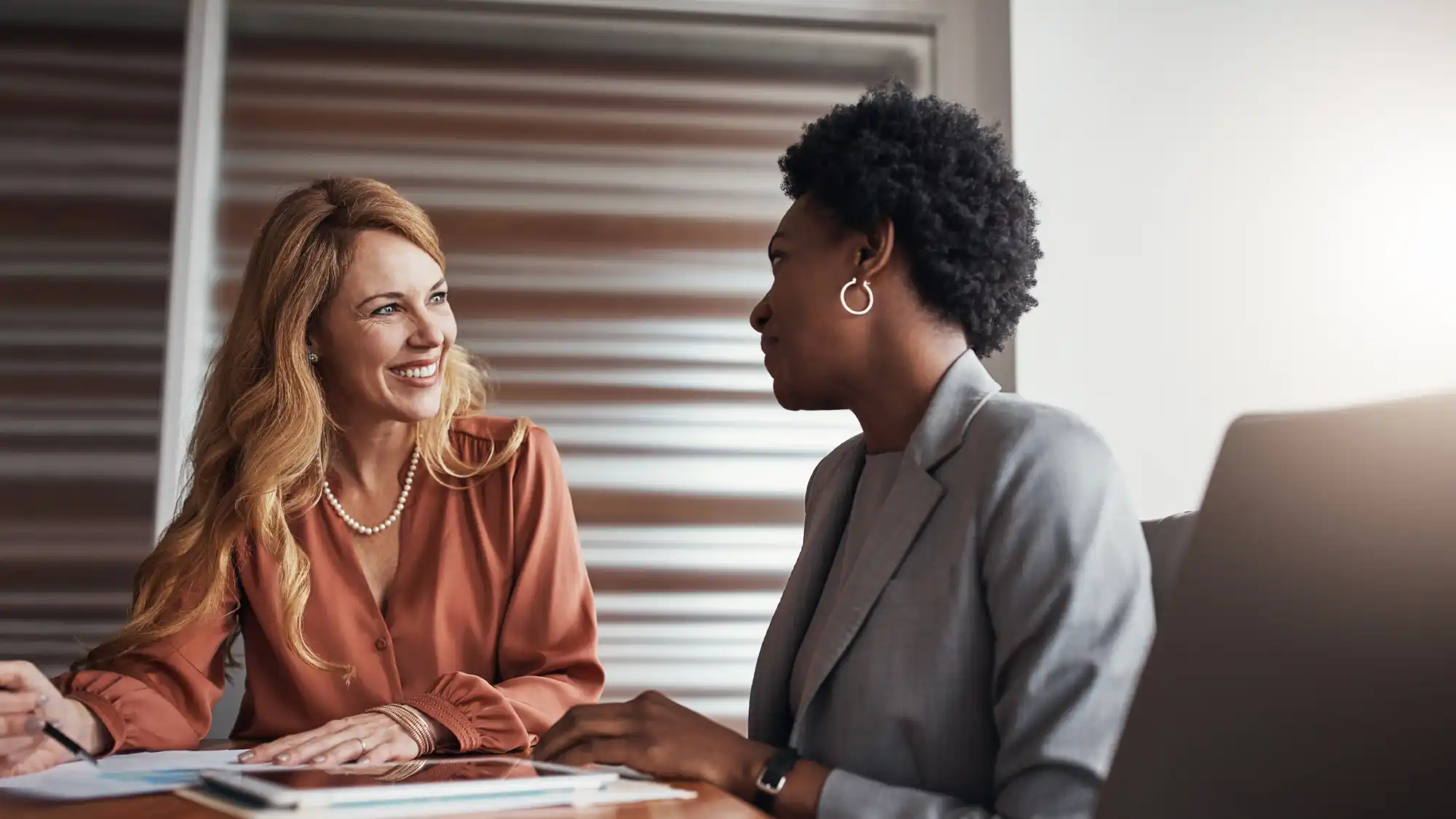 Two businesswomen smiling during a meeting at a conference table