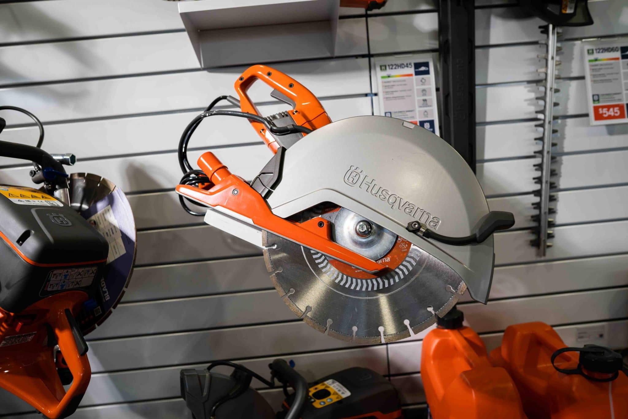 Husqvarna circular saw with metal blade displayed on a store wall with other tools nearby.