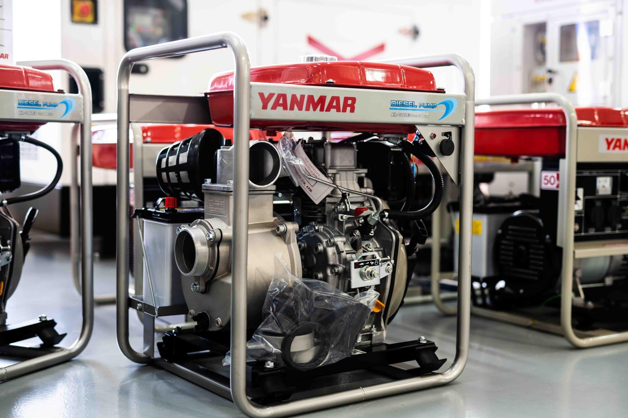 Yanmar diesel pump with red top and metal frame placed indoors on a gray floor.