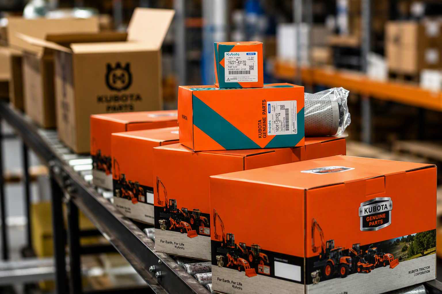 Stack of orange Kubota Genuine Parts boxes lined up on a conveyor belt in a warehouse.