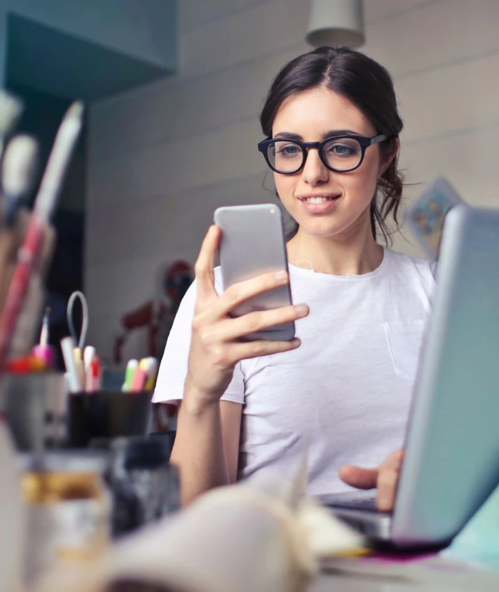 Fotka slečny na telefonu když právě zadává doporučení nemovitosti aby získala svou odměnu.