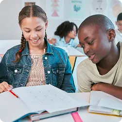 Two students smiling and working together on a classroom assignment