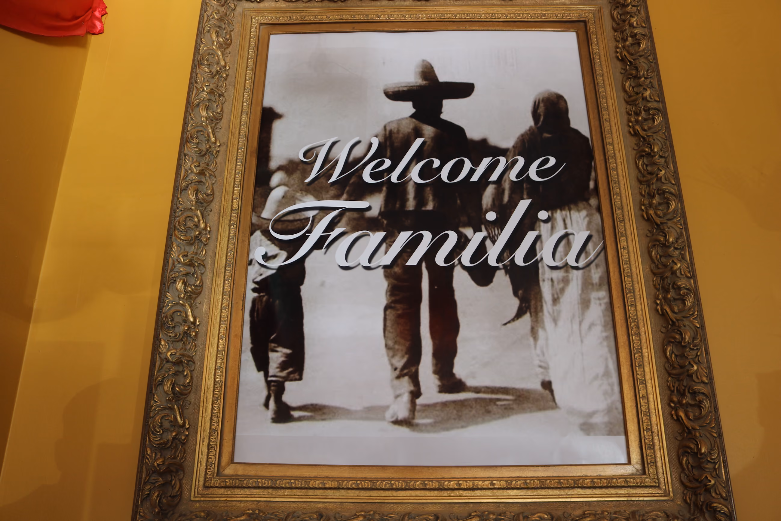 Framed sepia photo of a family walking away, overlaid with text saying 'Welcome Familia'.
