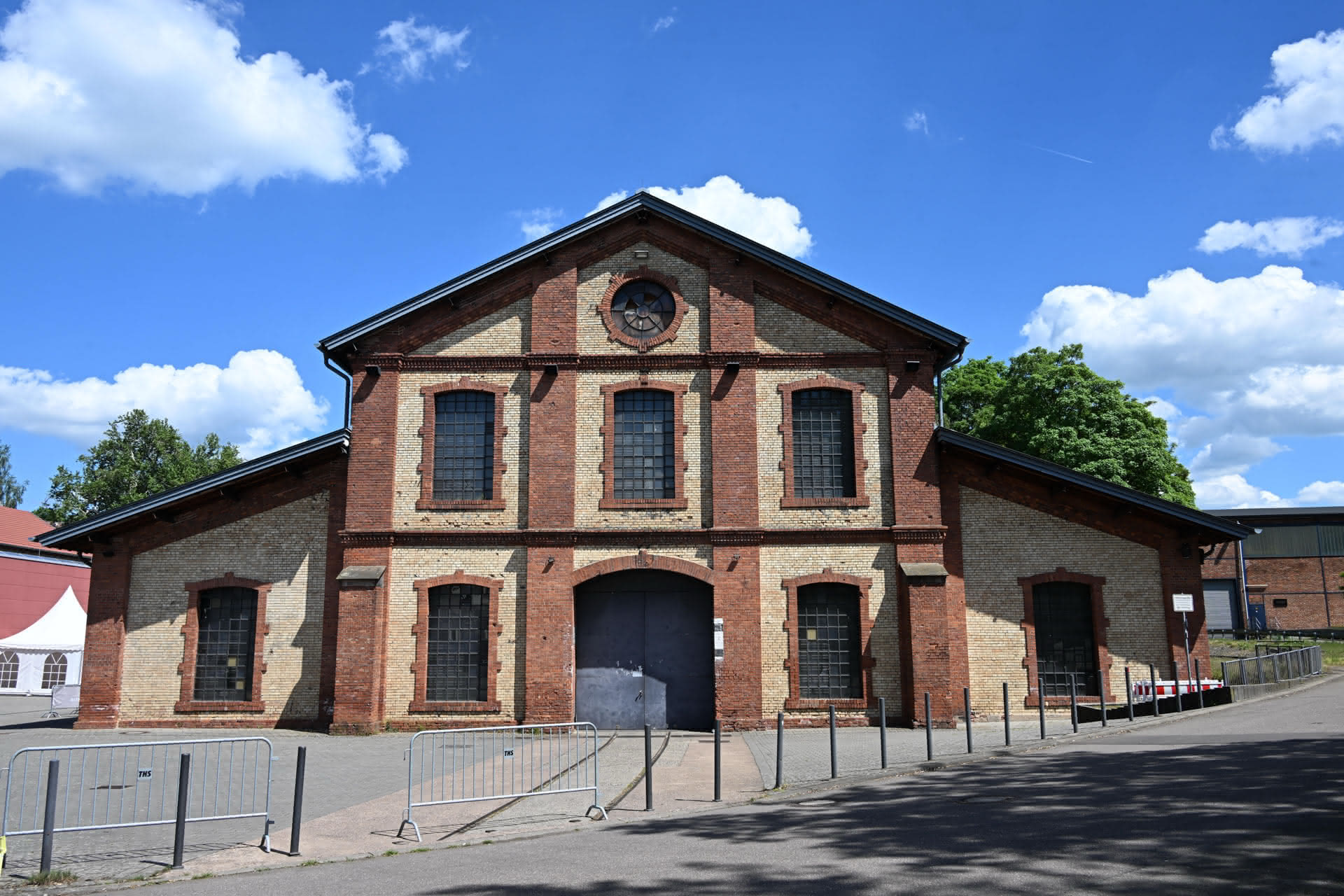 Altes Industriegebäude aus rotem und hellem Backstein mit großen Fenstern und blauem Himmel.
