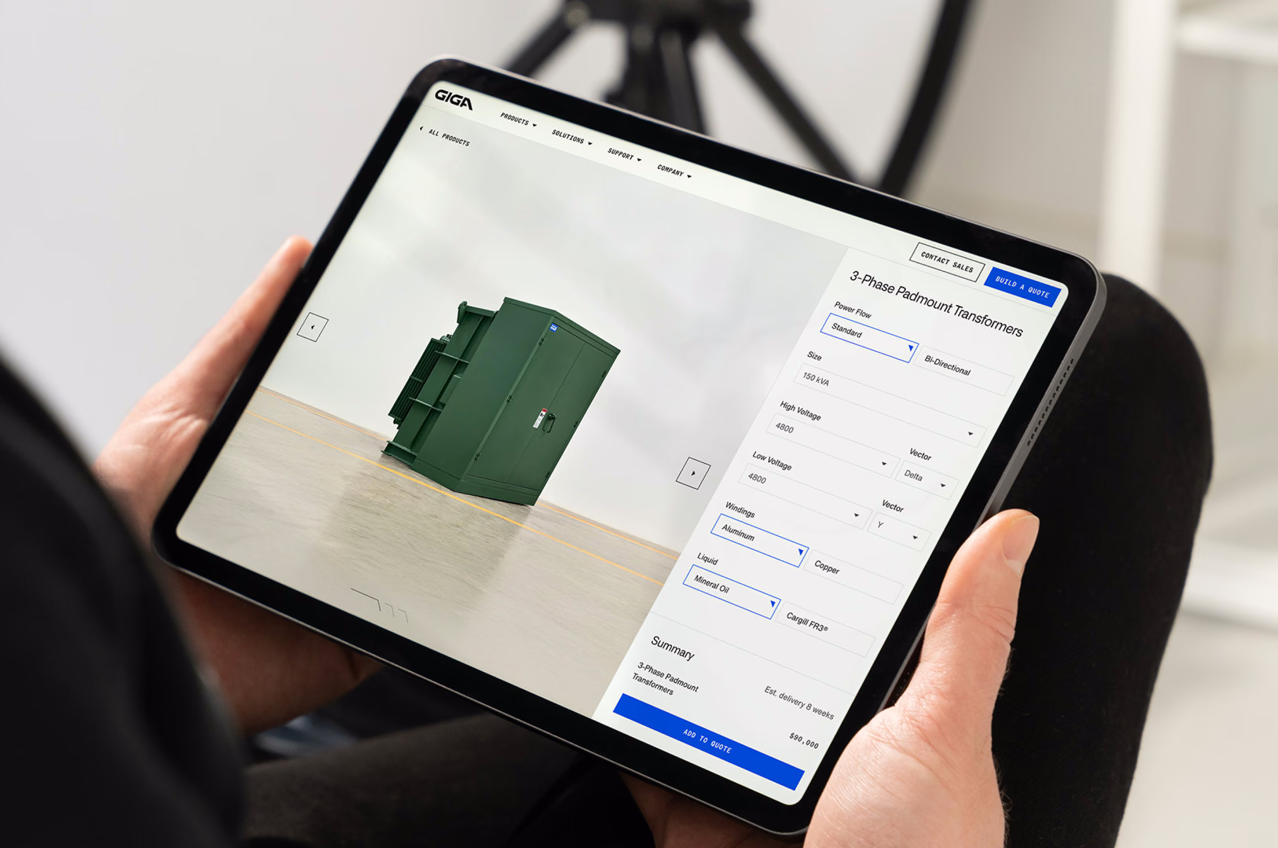 Hands holding an iPad with Giga's product configurator for a green 3-phase padmount transformer.