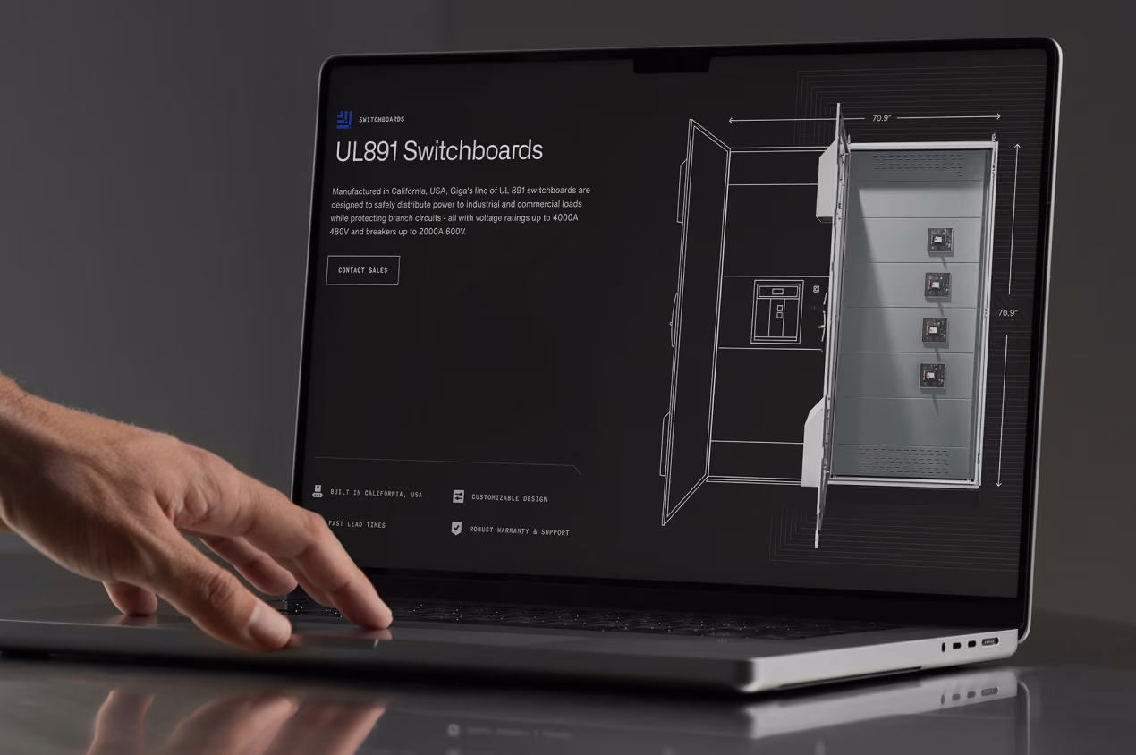 Hand at a laptop showing Giga's UL891 Switchboards page with a wireframe drawing of an open switchboard cabinet.