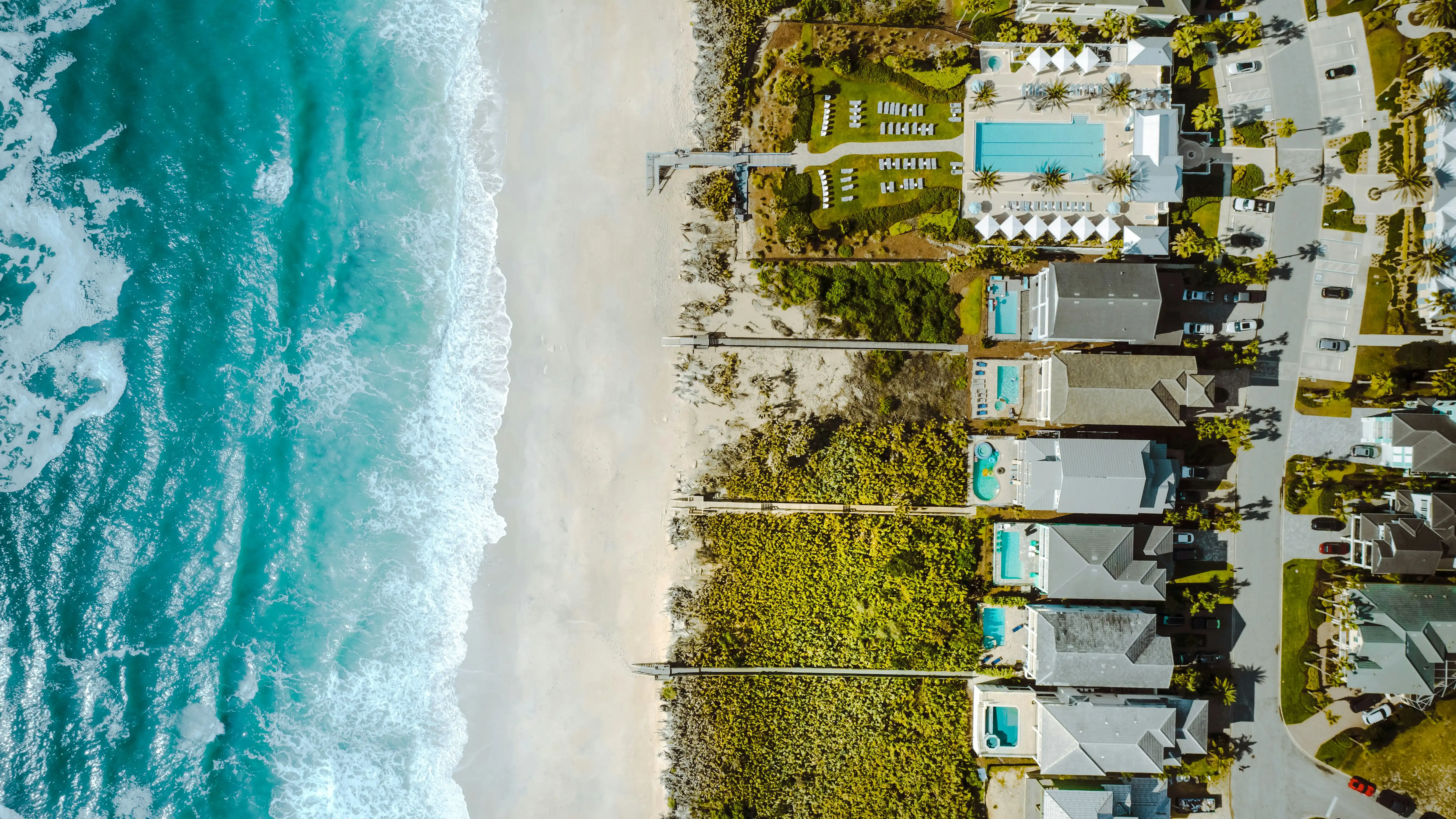 Aerial view of beachfront homes with pools along the South Florida coast