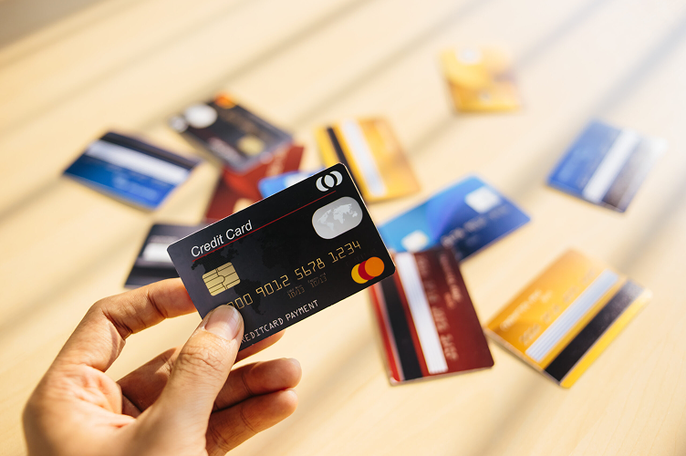 Hand holding a credit card above several other cards on a table