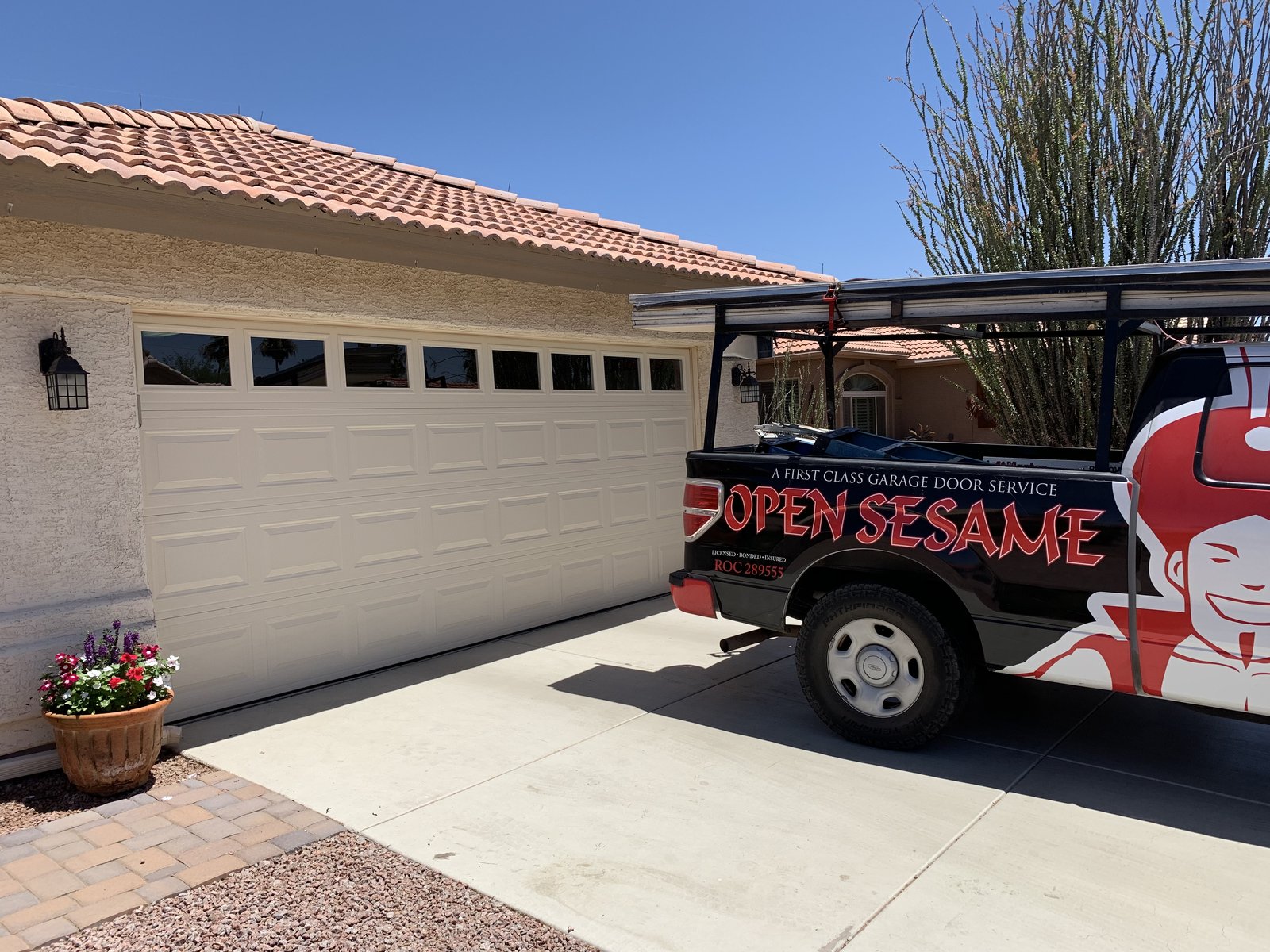 Open Sesame service truck outside a three bay white garage door installation