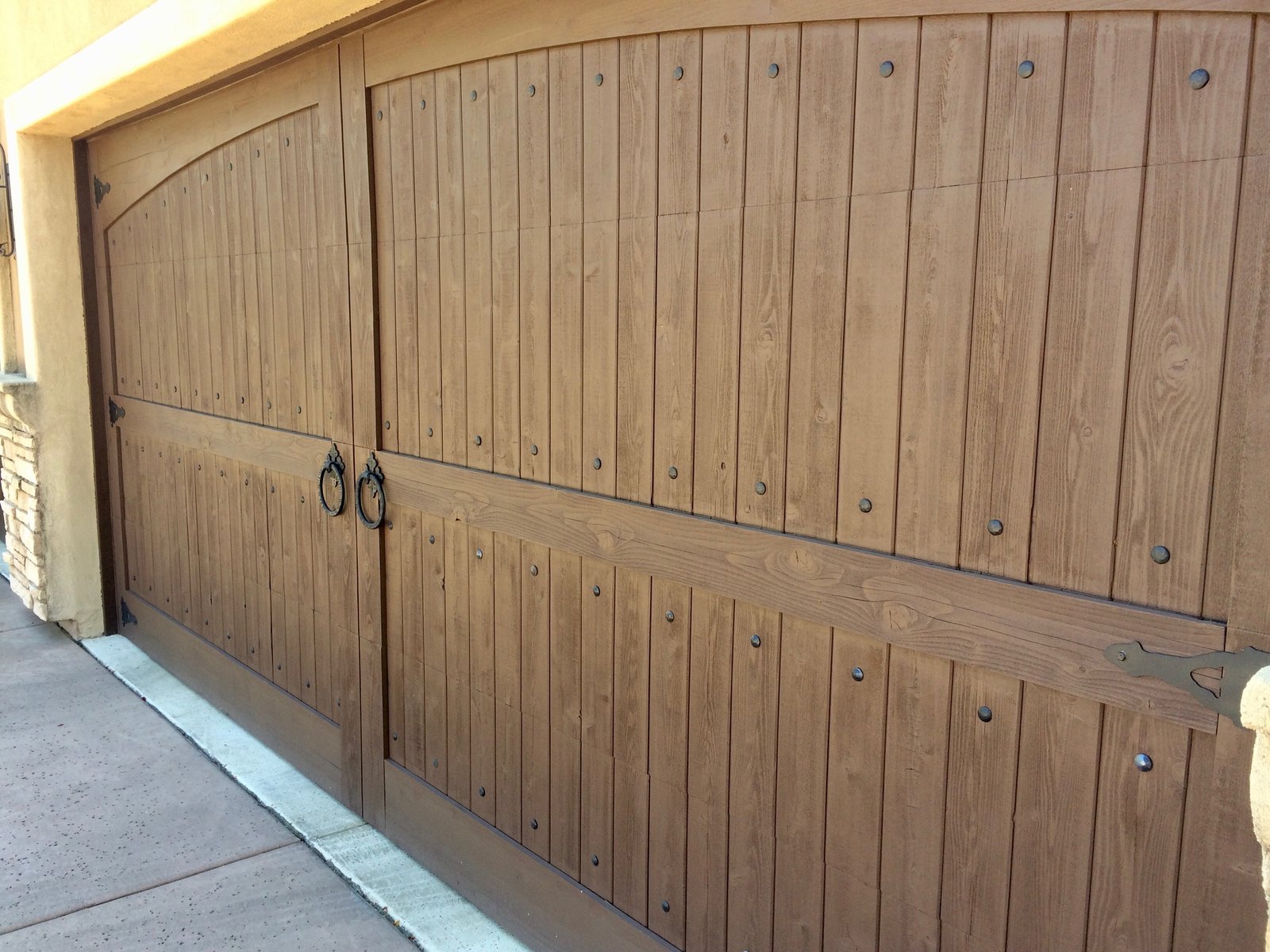 Arched wood plank garage door with decorative hardware
