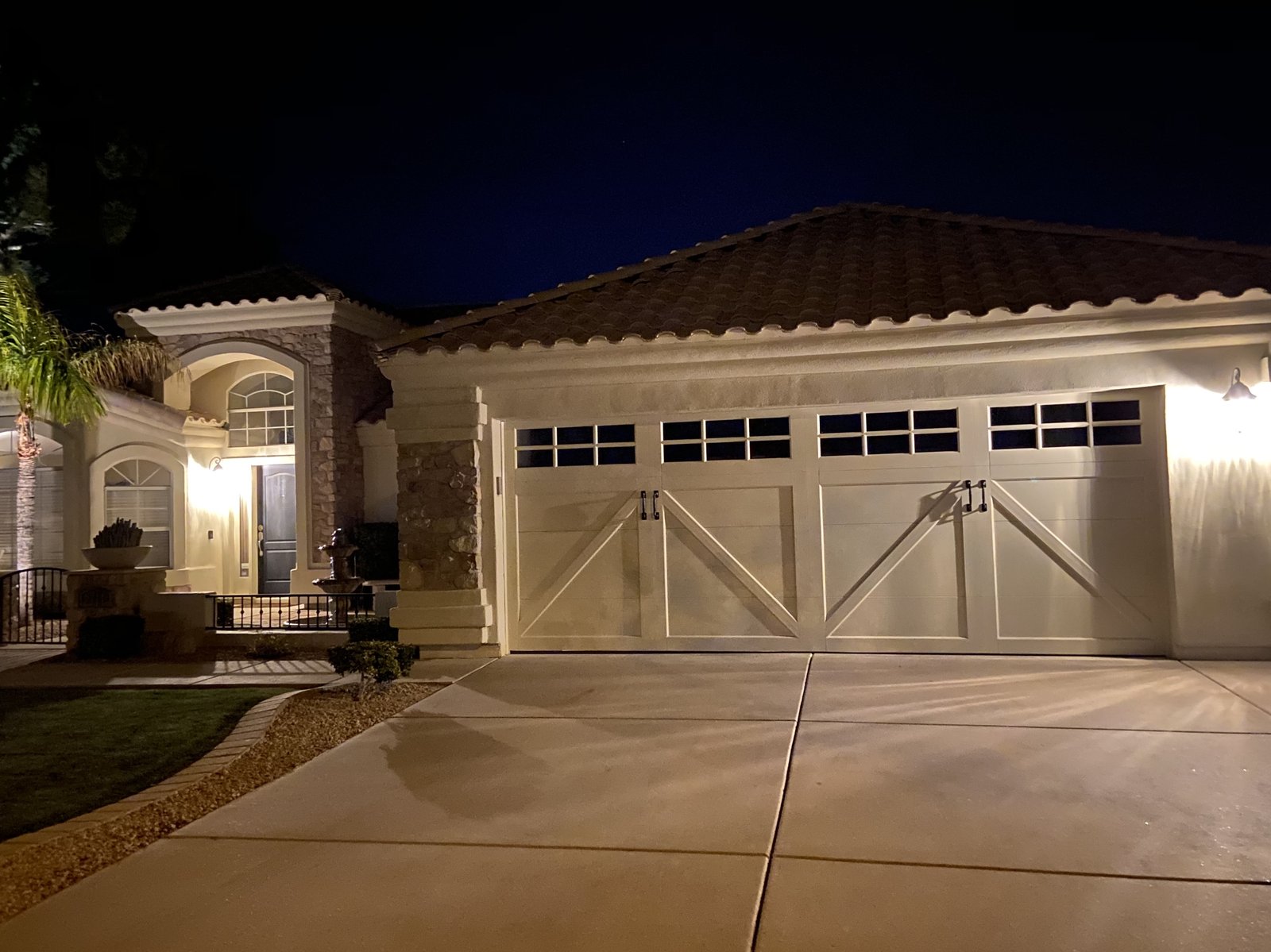 Cream carriage style garage doors lit at dusk