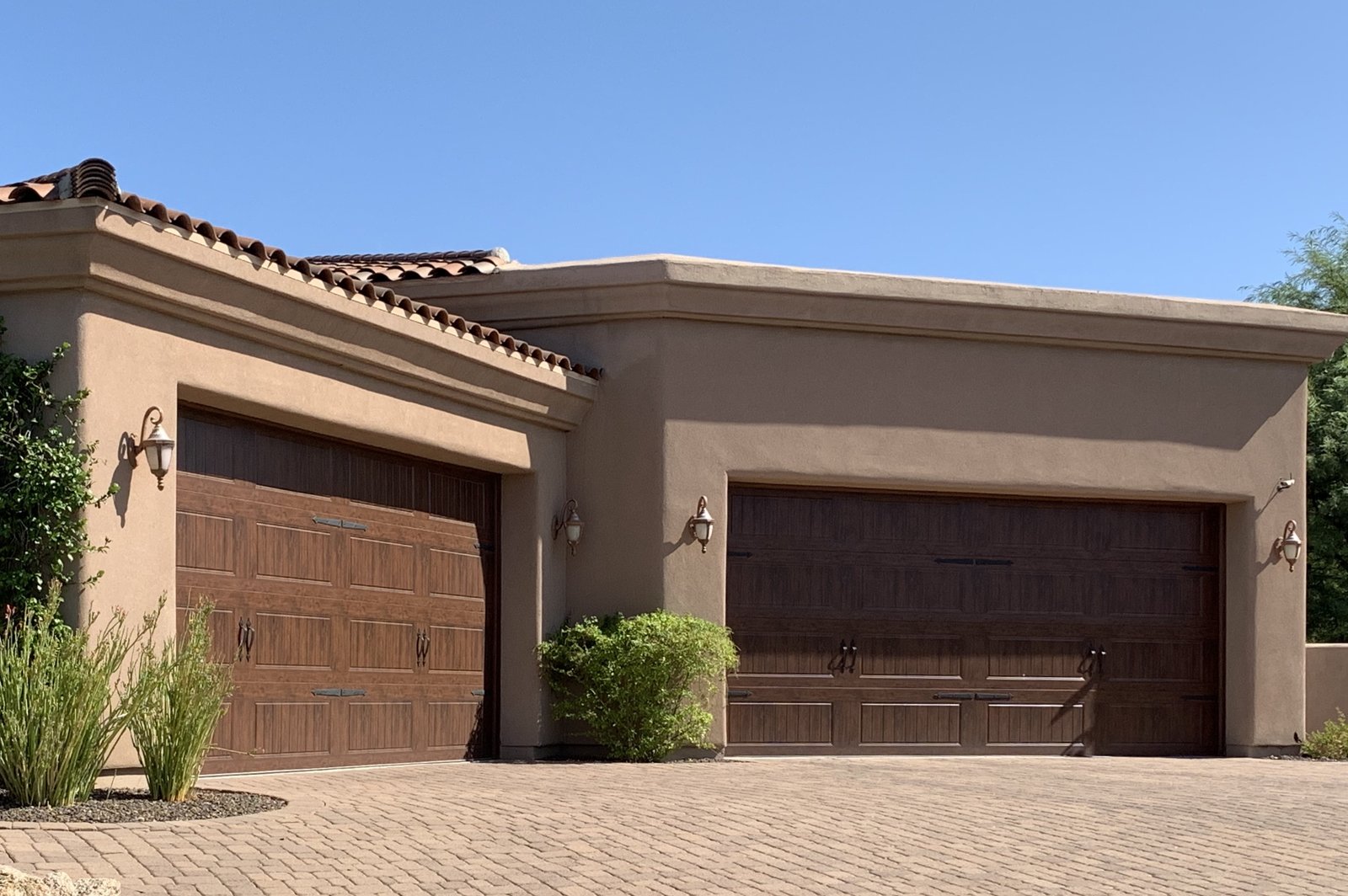 Two dark woodgrain garage doors on a stucco home