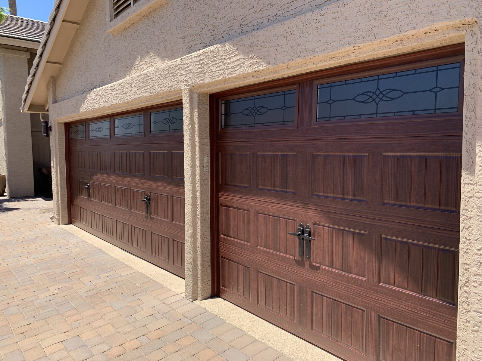 Woodgrain garage doors above a paver driveway