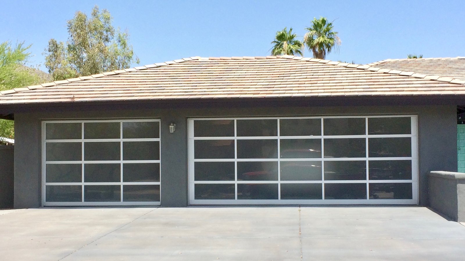 Full view glass garage doors on a grey single storey home