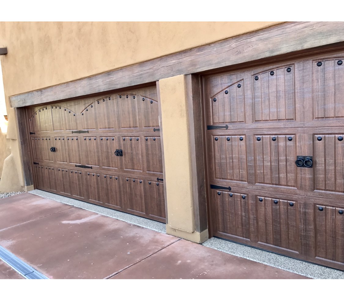 Two dark carriage style garage doors on a stucco home