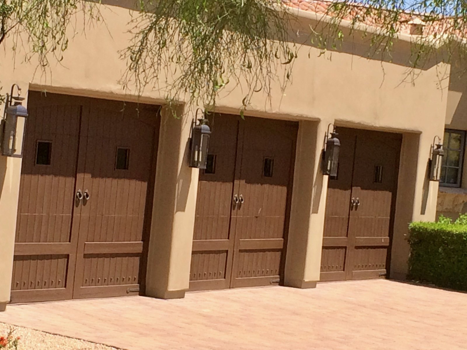 Three woodgrain garage doors with wall sconces between them