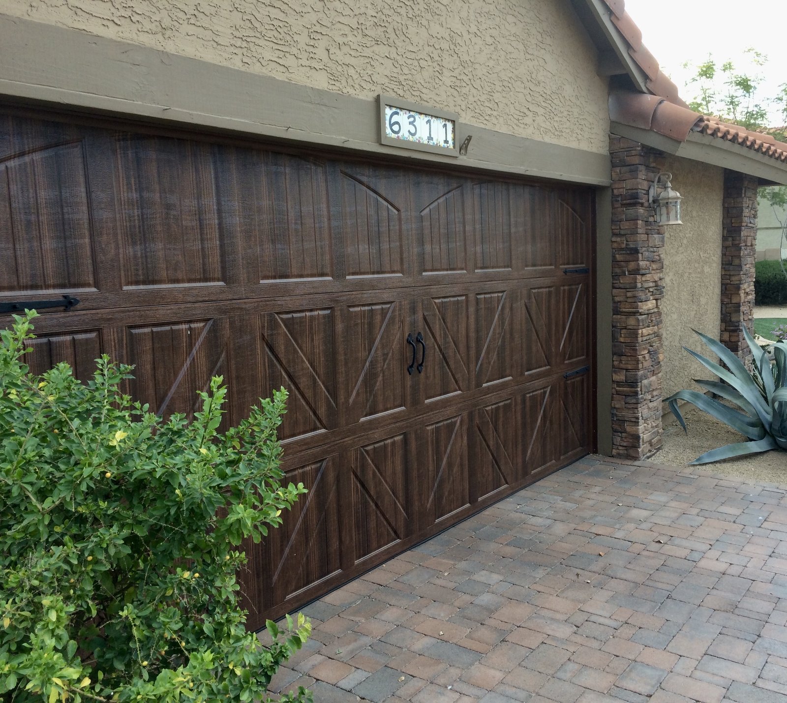 Dark carriage style garage door at a paver entry