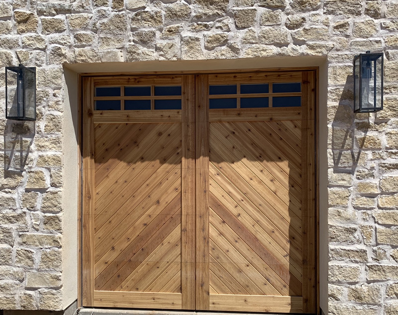 Chevron pattern cedar garage door set in a stone wall