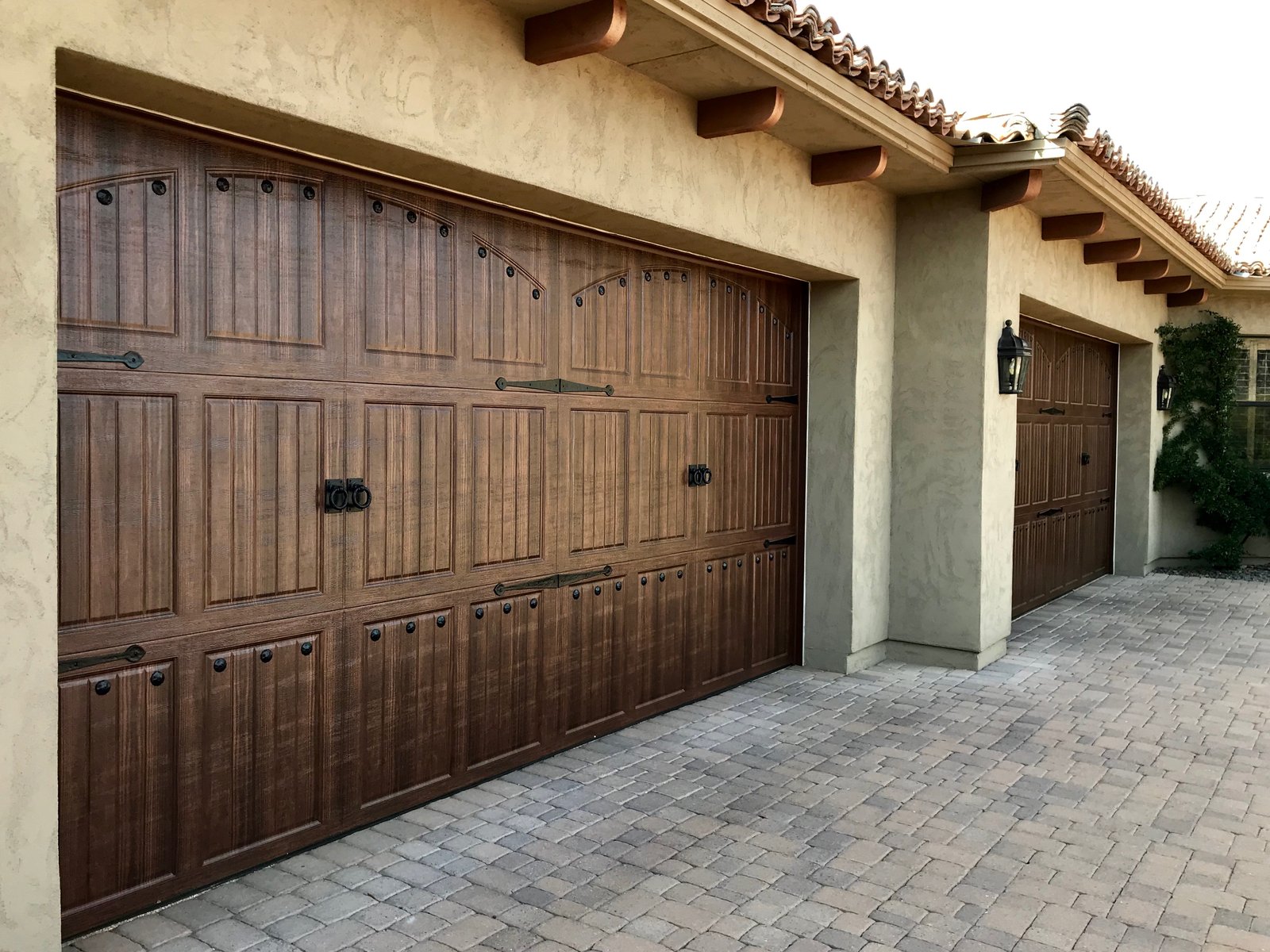 Woodgrain carriage style garage doors above a paver driveway on a Phoenix Metro home