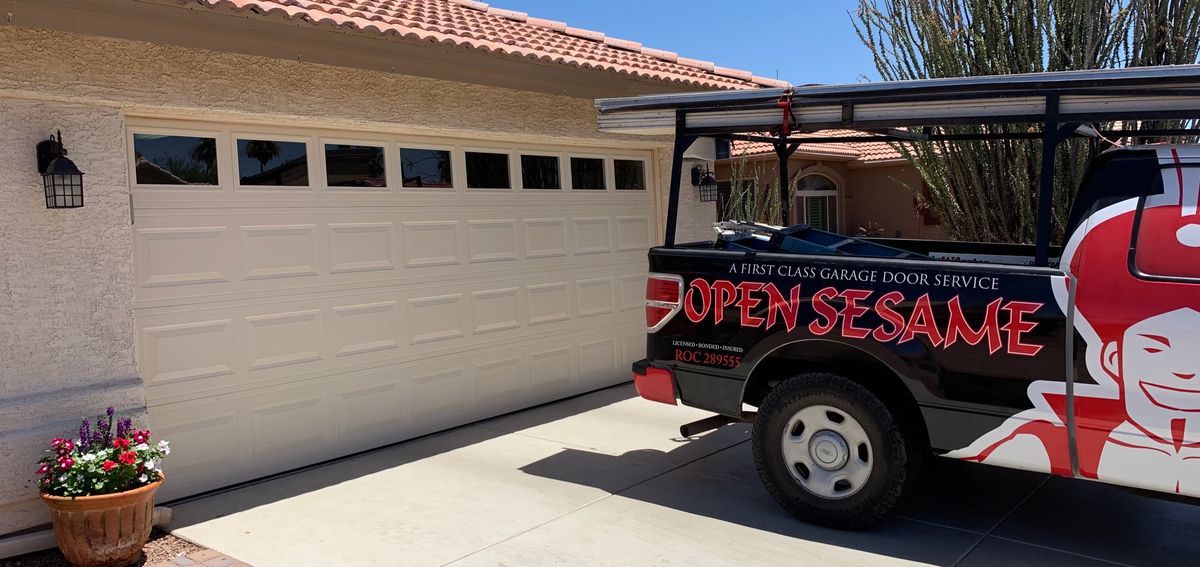 Open Sesame service truck on a driveway beside a completed garage door