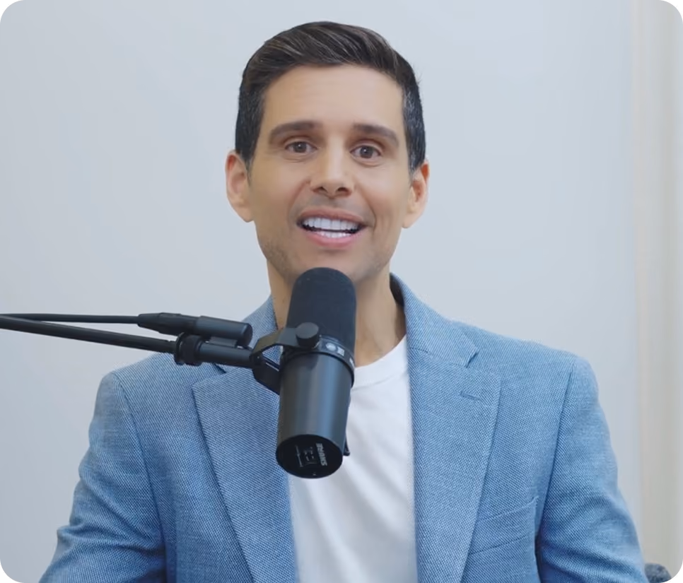 Alejandro Chabán in light blue blazer speaking into a studio microphone against a plain background.