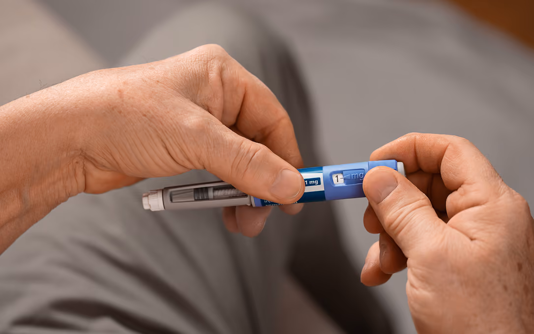 Close-up of hands adjusting a blue insulin pen showing a 1 mg dose setting.