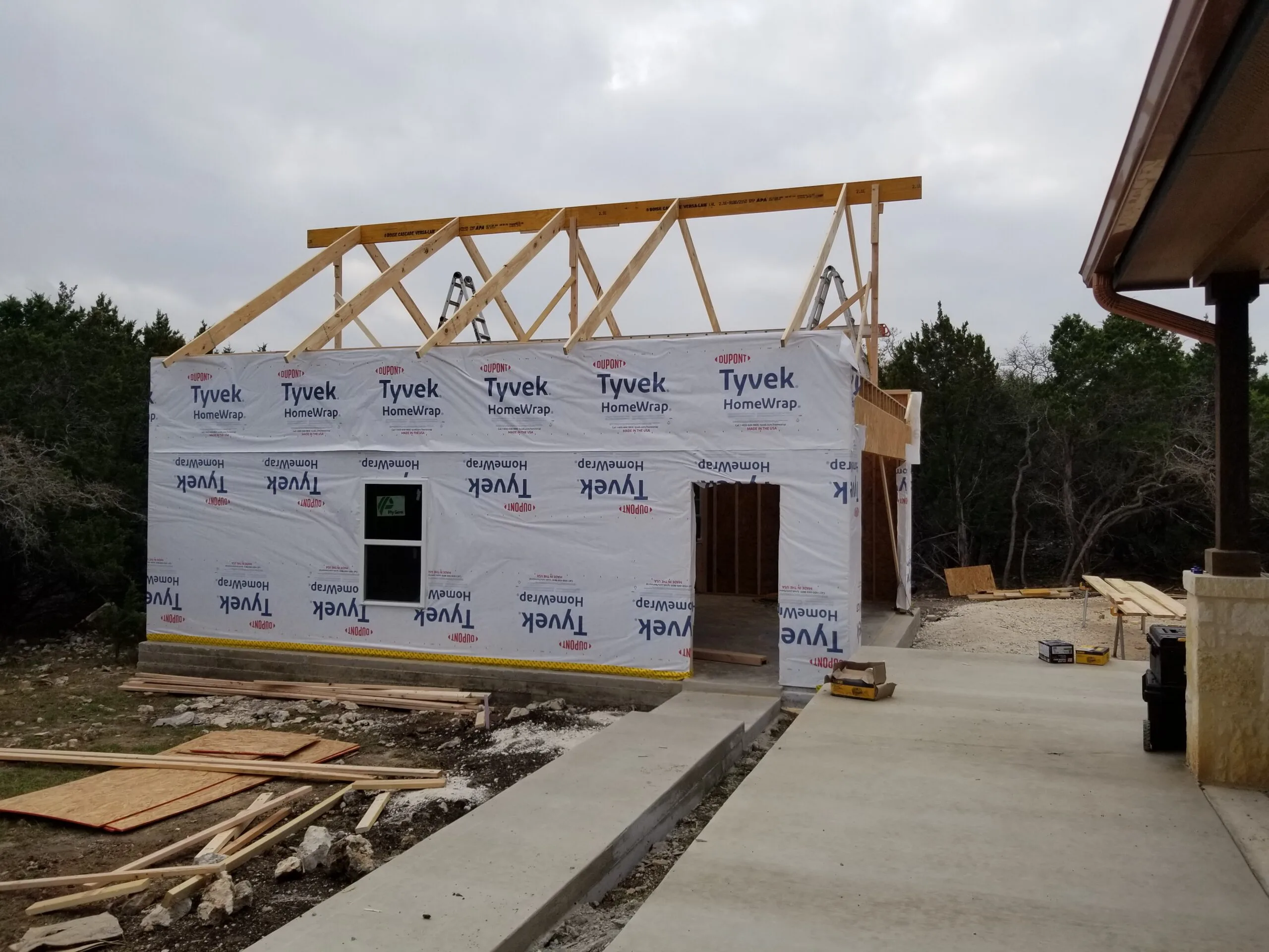 Exposed roof trusses over a housewrapped garage addition during framing