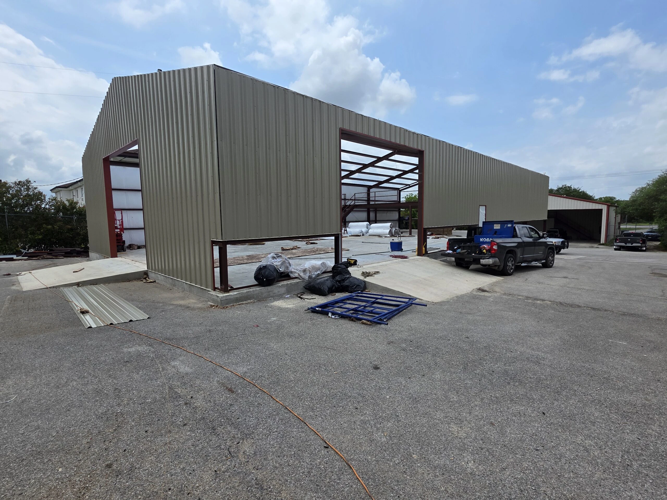 Steel commercial building with open bays and a paved lot at the Blanco AC Plumbing site