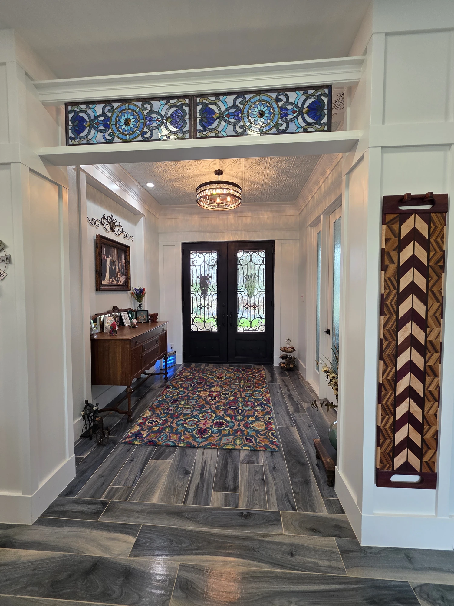 Entry hall with iron and glass double doors, a stained glass transom, and a pressed tin ceiling