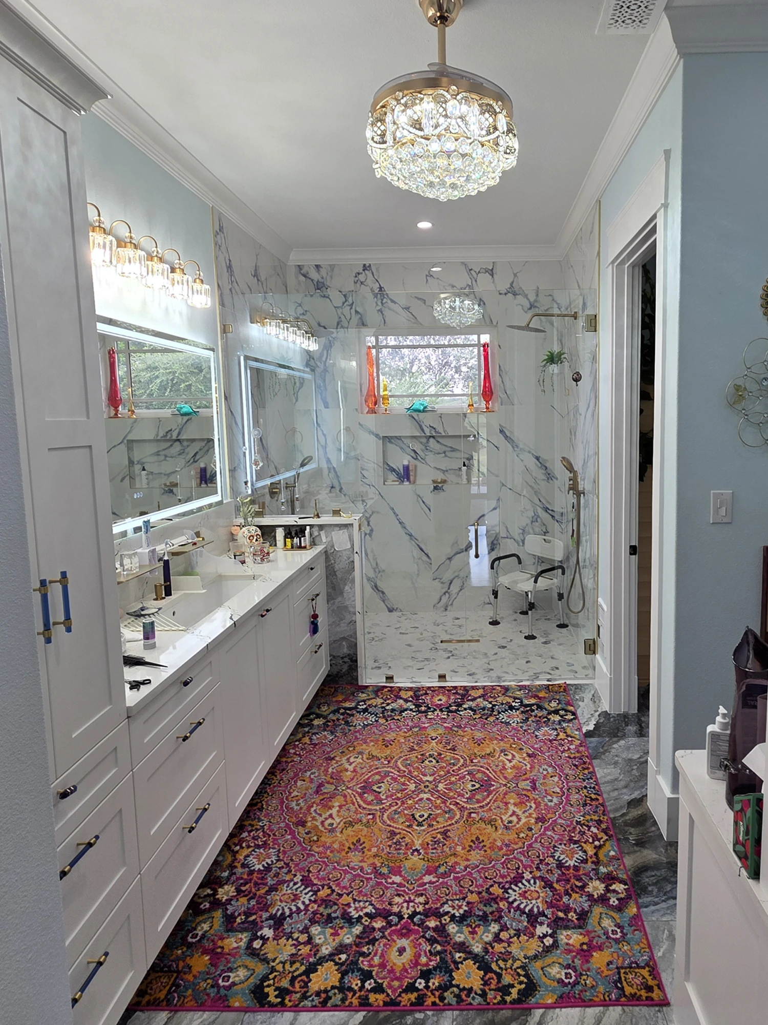 Primary bath with marble walls, a walk-in glass shower, and a double vanity