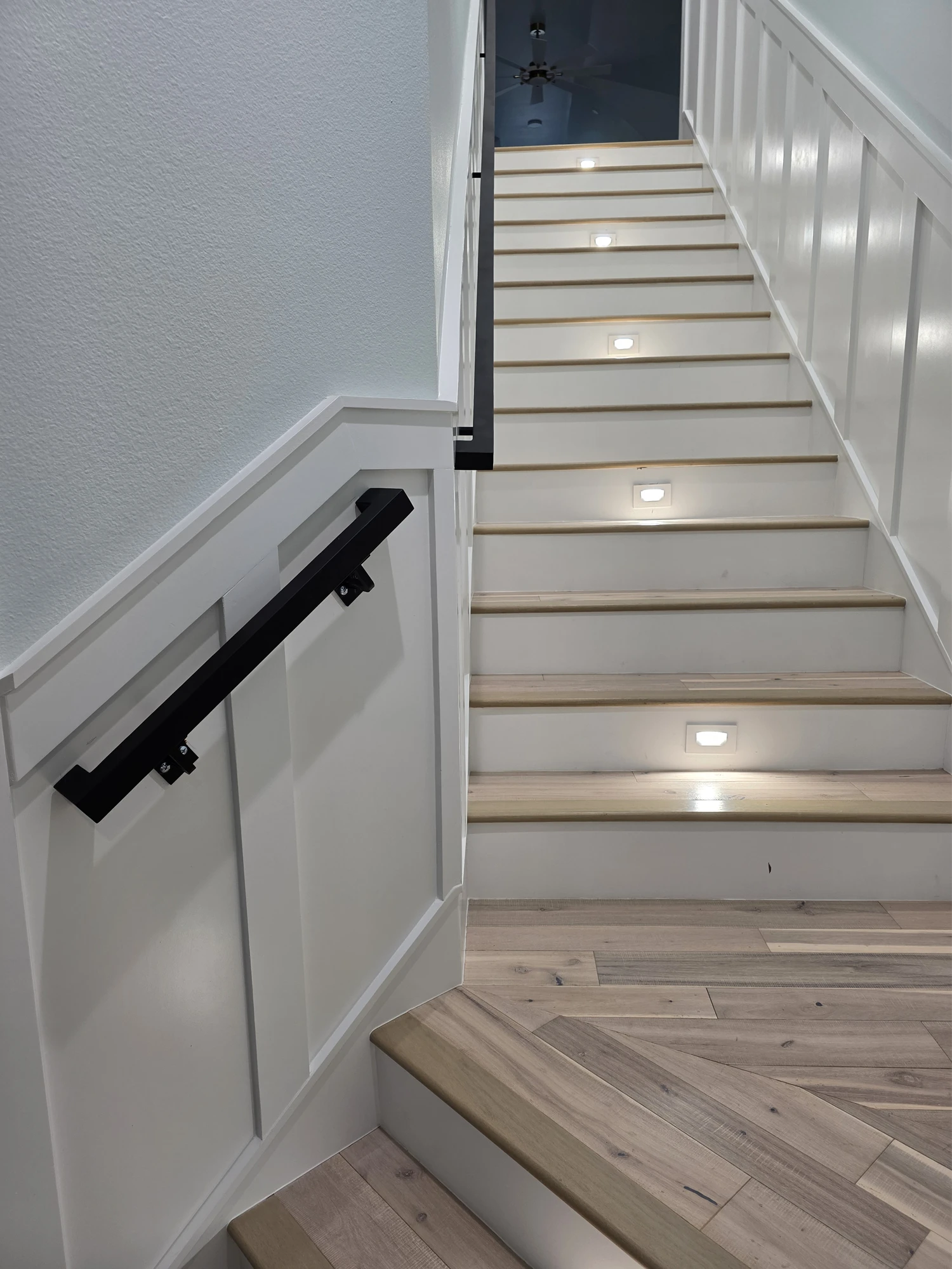 Interior staircase with board-and-batten wainscot, wood treads, and recessed step lighting