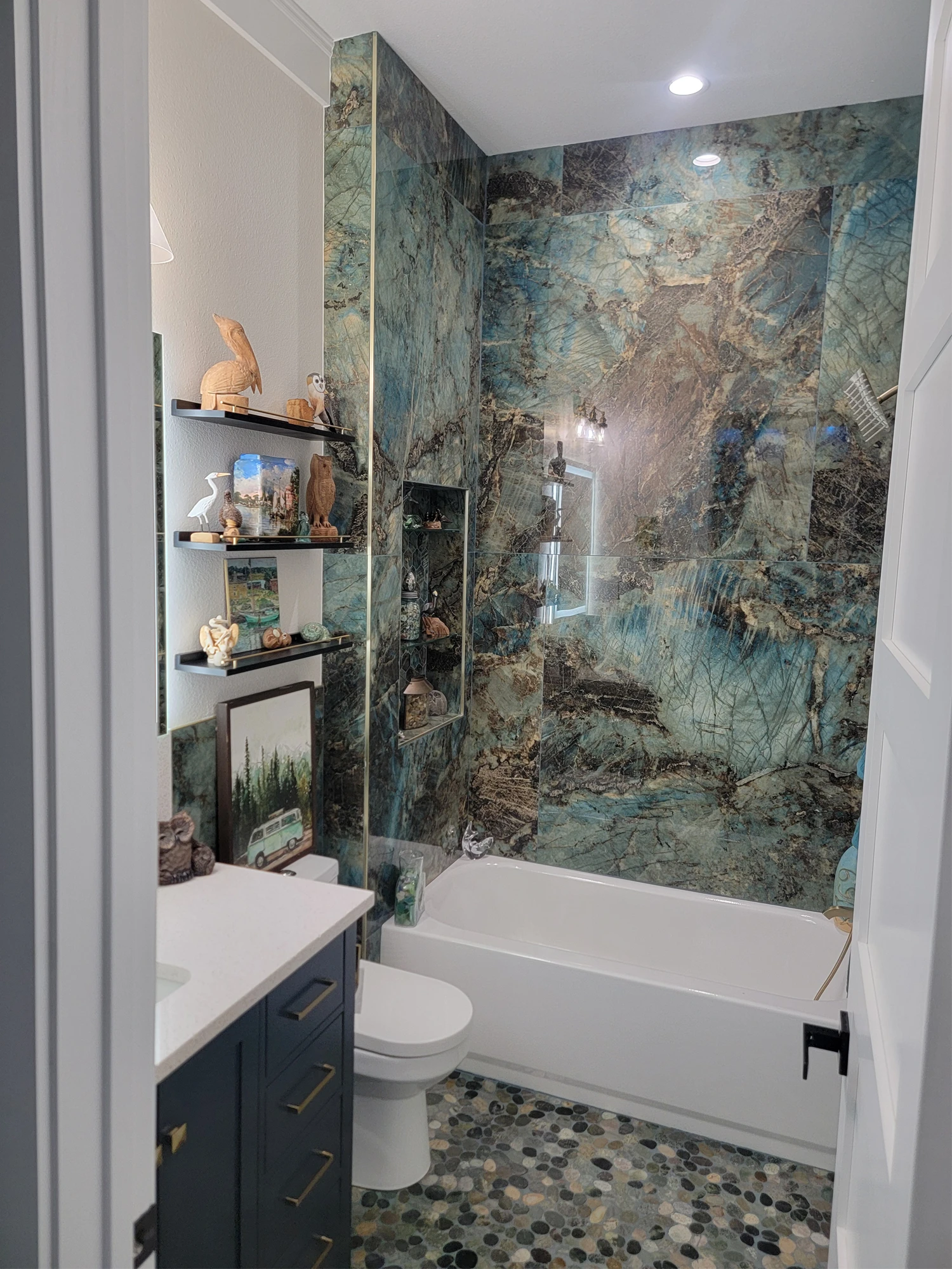 Guest bath with a floor-to-ceiling blue quartzite tub surround and pebble tile floor