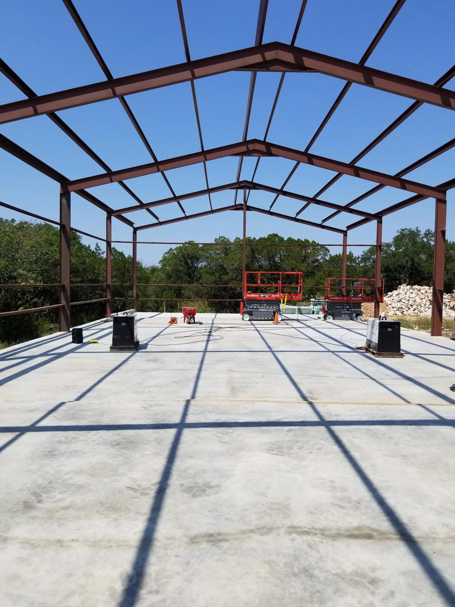 Looking up through the bare steel frame at the rafters over the newly poured slab
