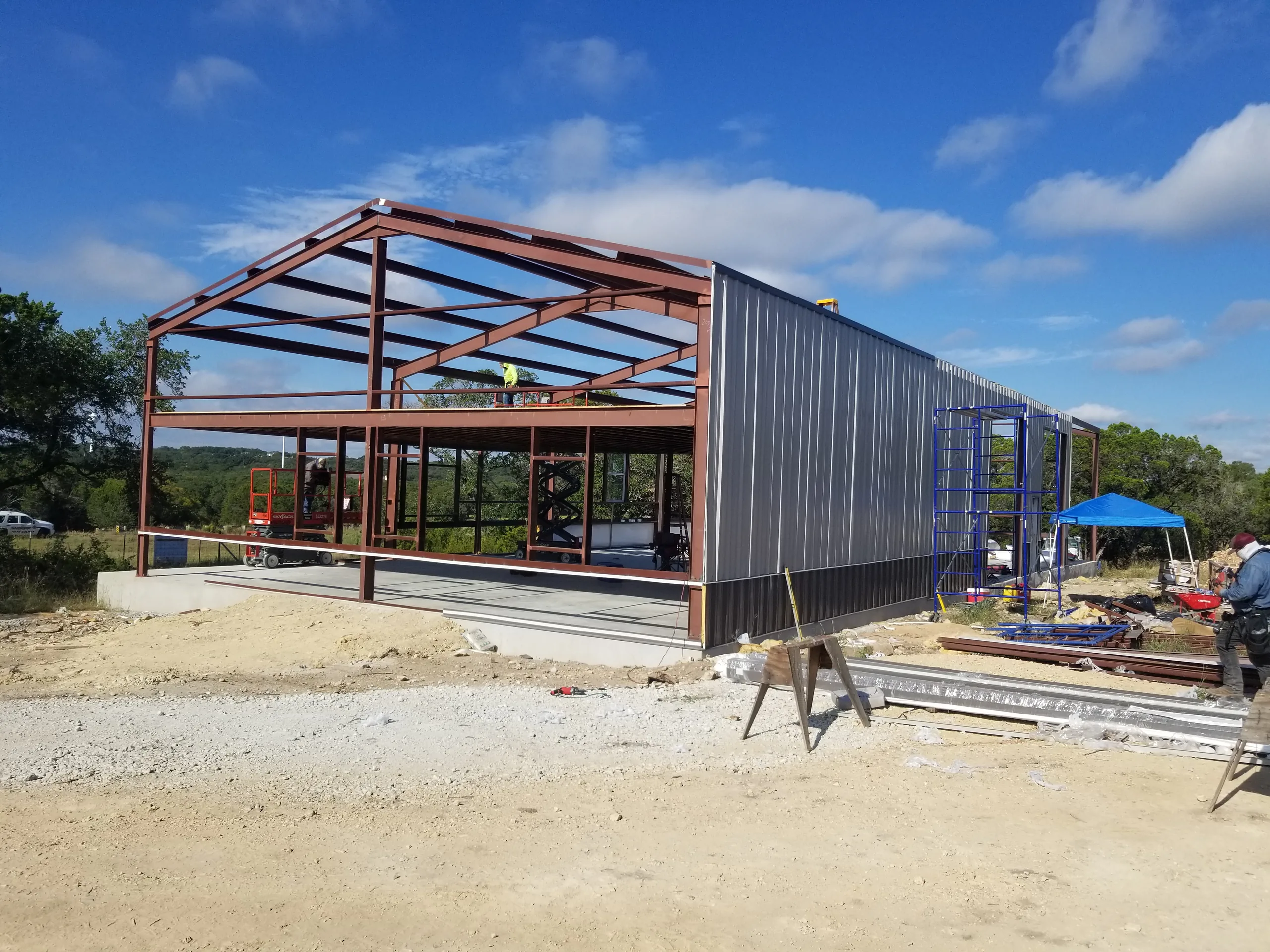 Long side wall sheeted in dark metal with the gable end still open steel frame