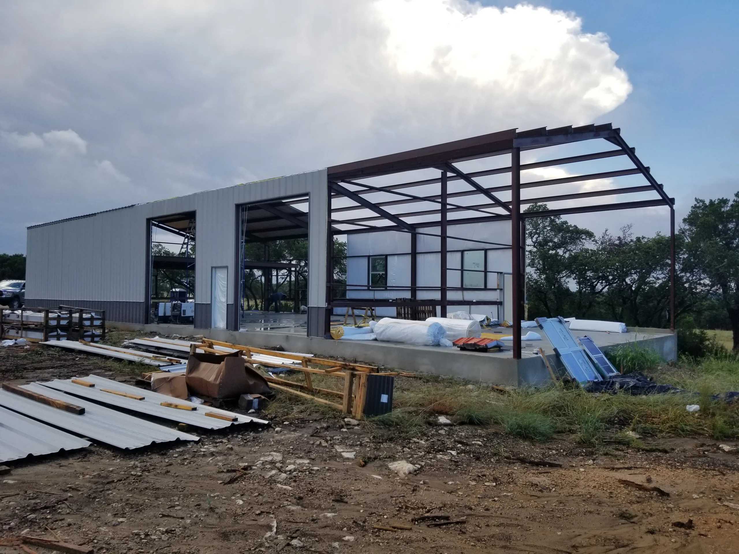 Light gray wall panels going up on the end wall with framed openings and insulation staged on the slab