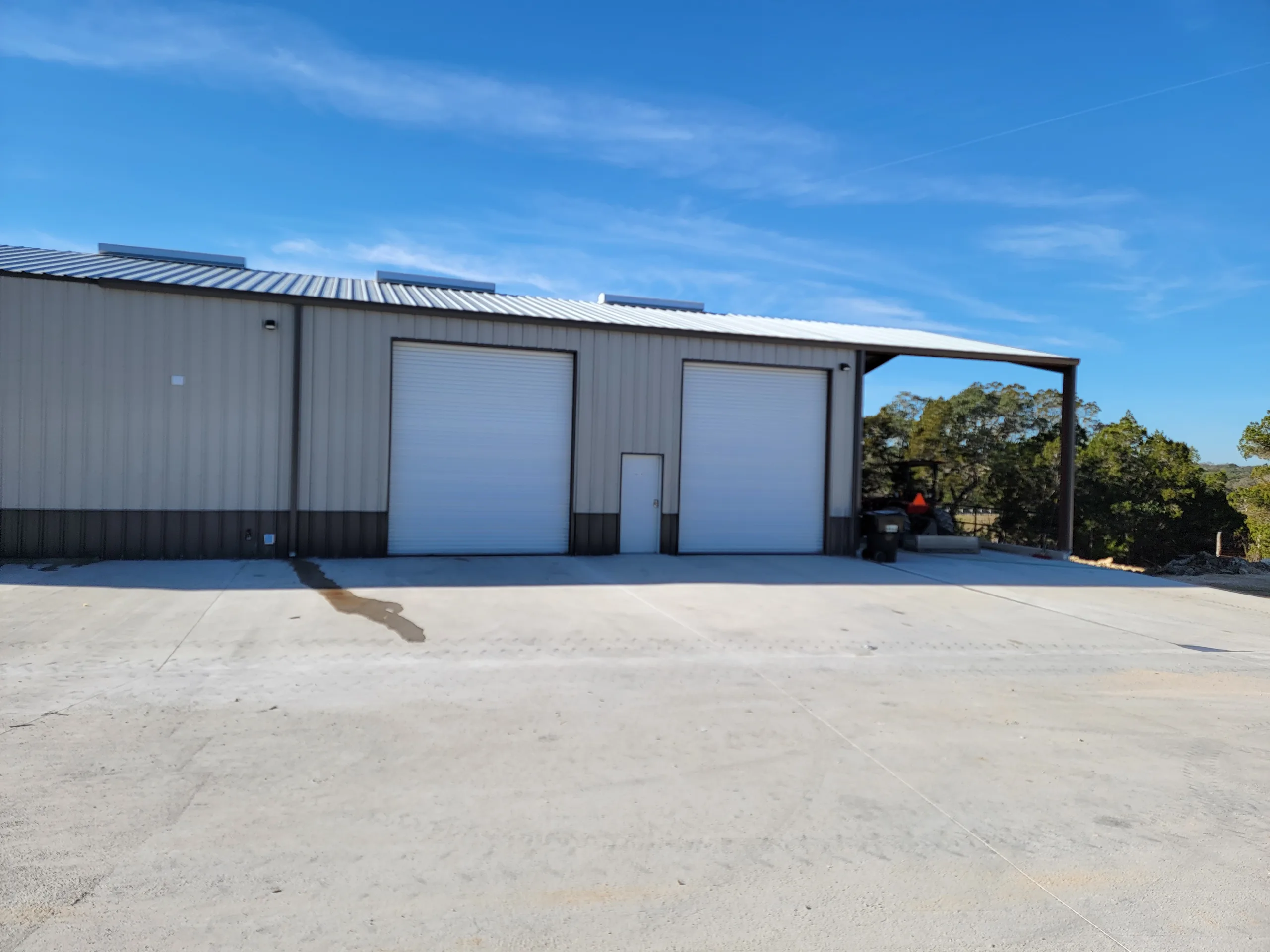 Two overhead doors and a man door on the finished building with a covered open bay at the end