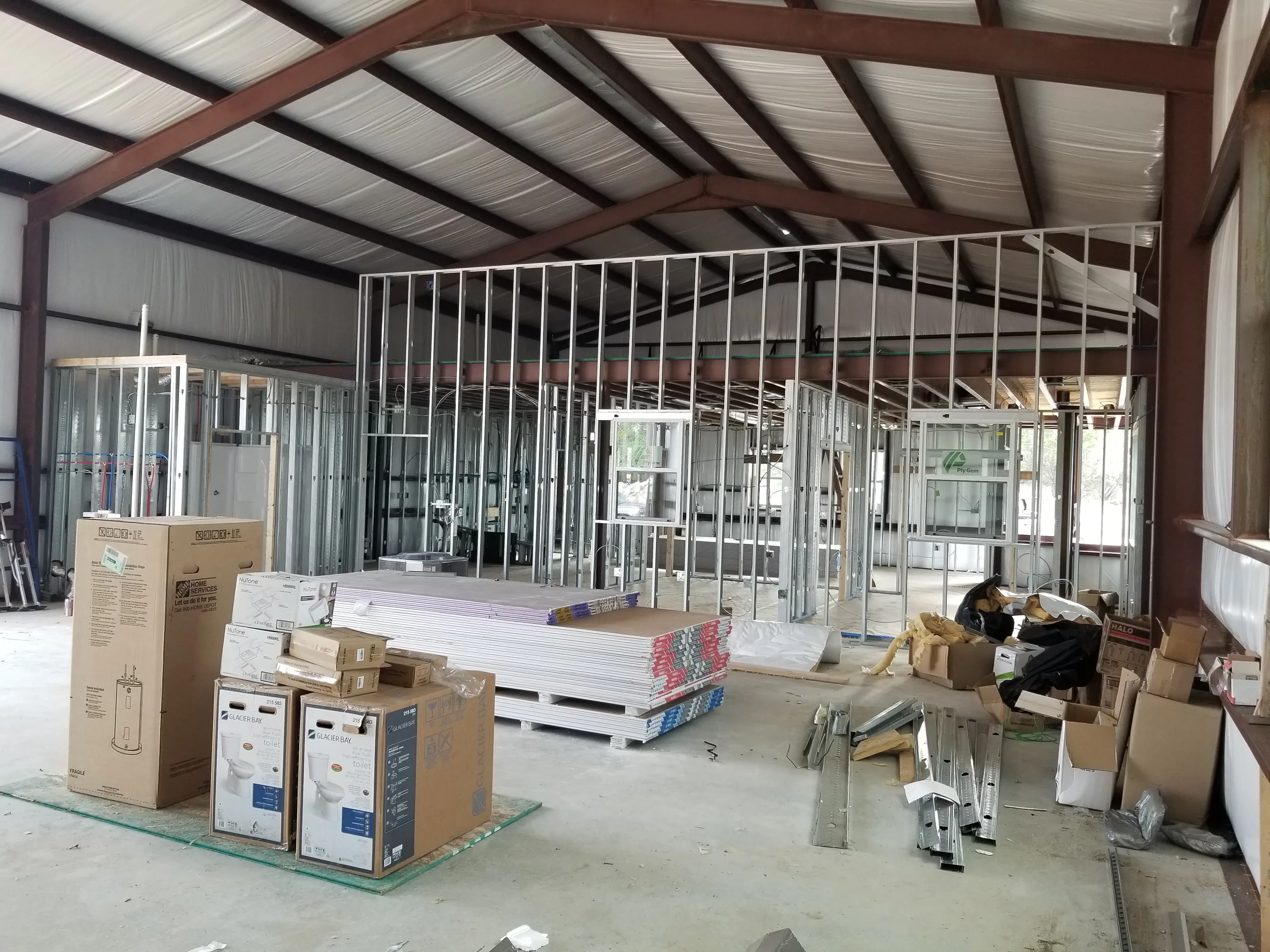 Steel stud office partitions framed out with water heaters and finish materials staged on the slab