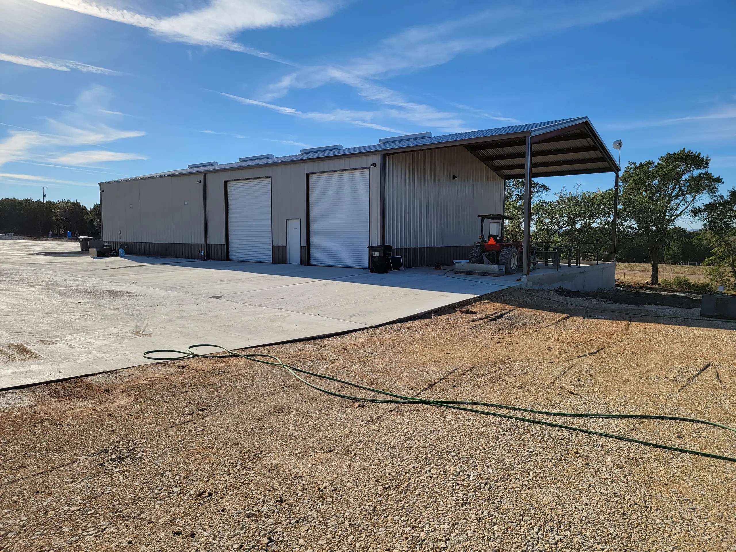 Finished commercial steel building with three overhead doors, dark wainscot, and a covered end bay