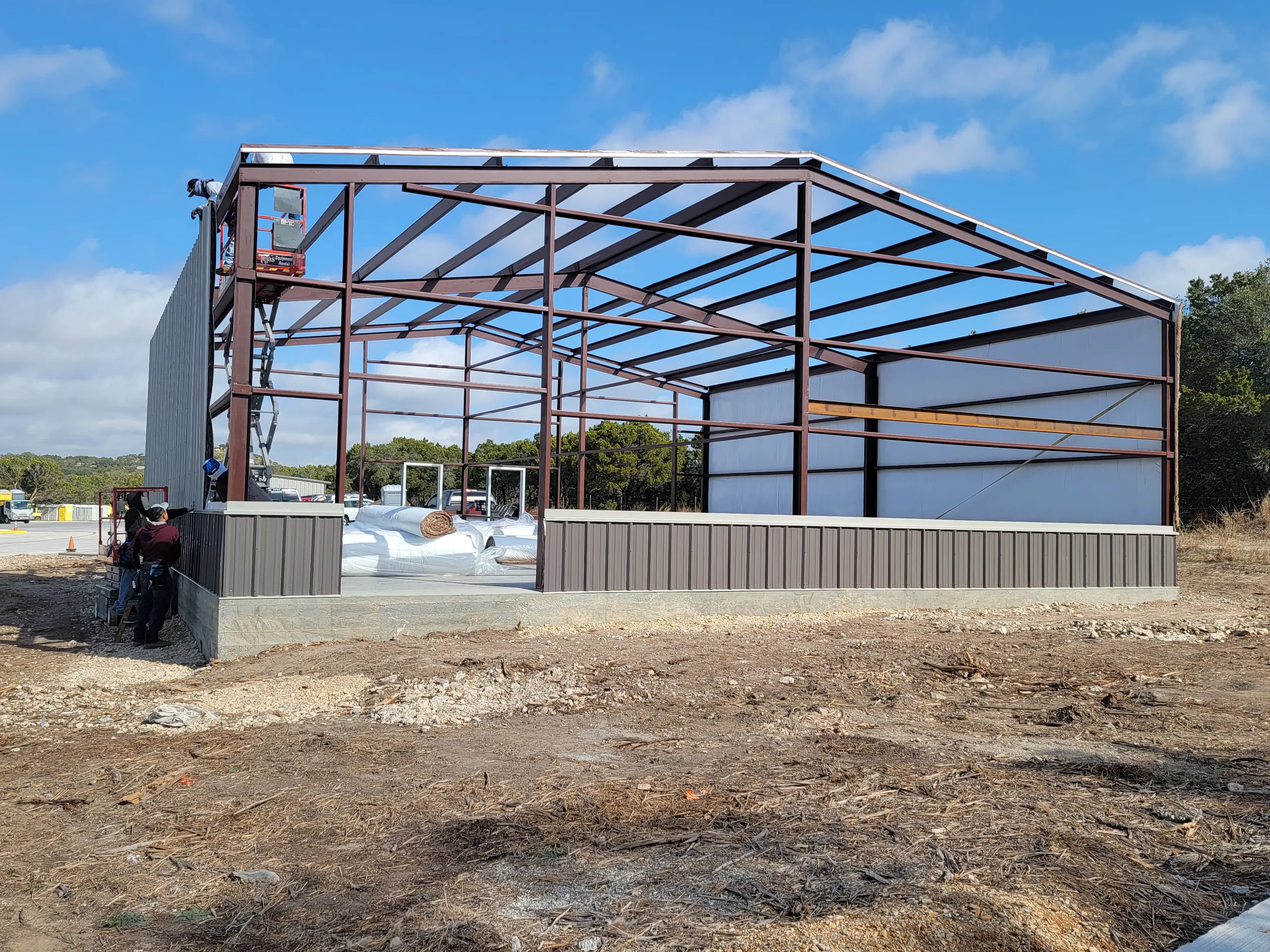 Commercial steel frame being erected with the first wall panels and dark metal wainscot installed