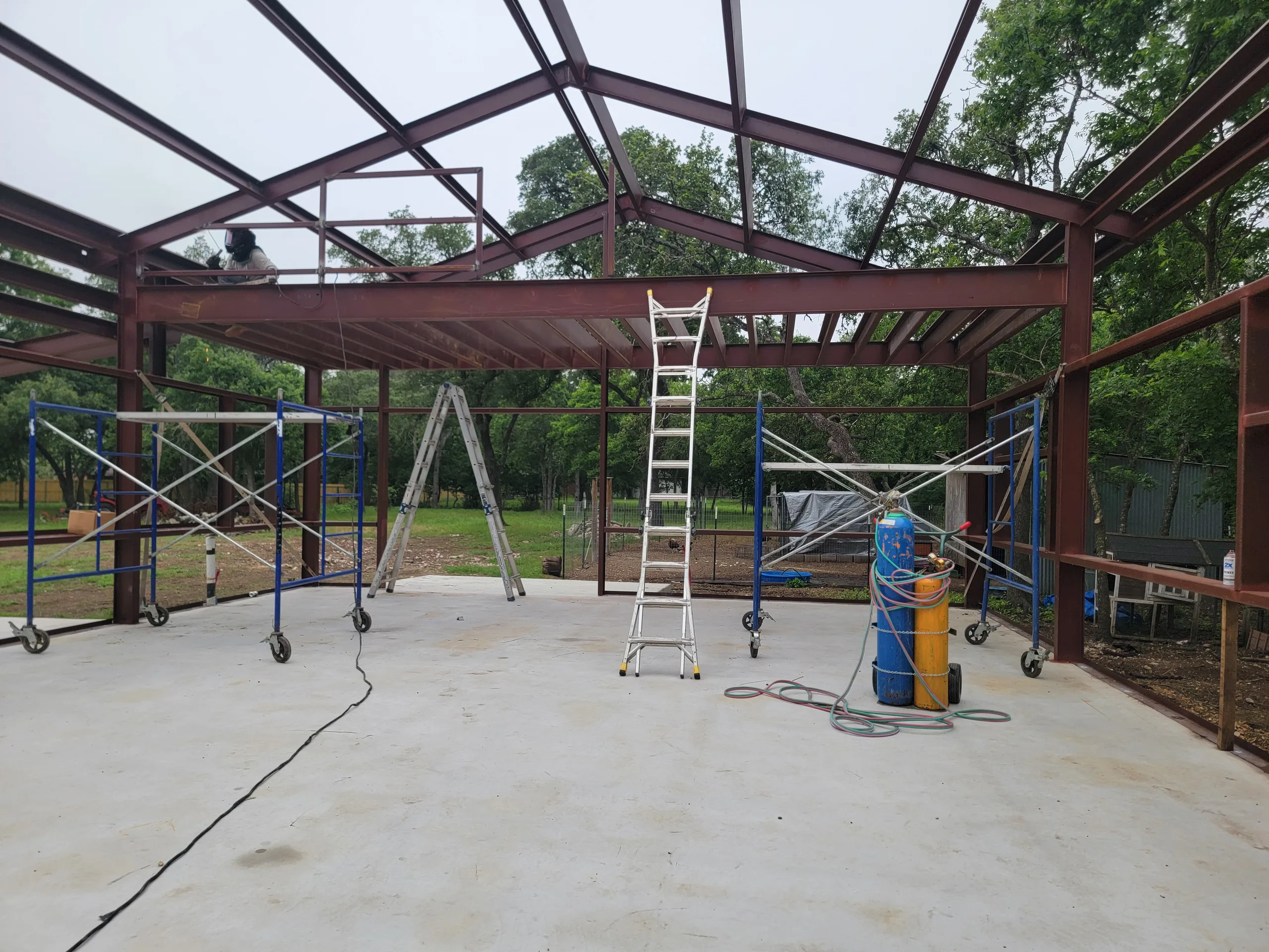 Steel frame and slab of the shop under construction with scaffolding and a ladder on site