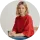 Smiling woman with blonde hair wearing a red sweater, seated and facing the camera.