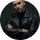 Confident man with a beard wearing a black leather jacket, posing with crossed arms against a dark background.