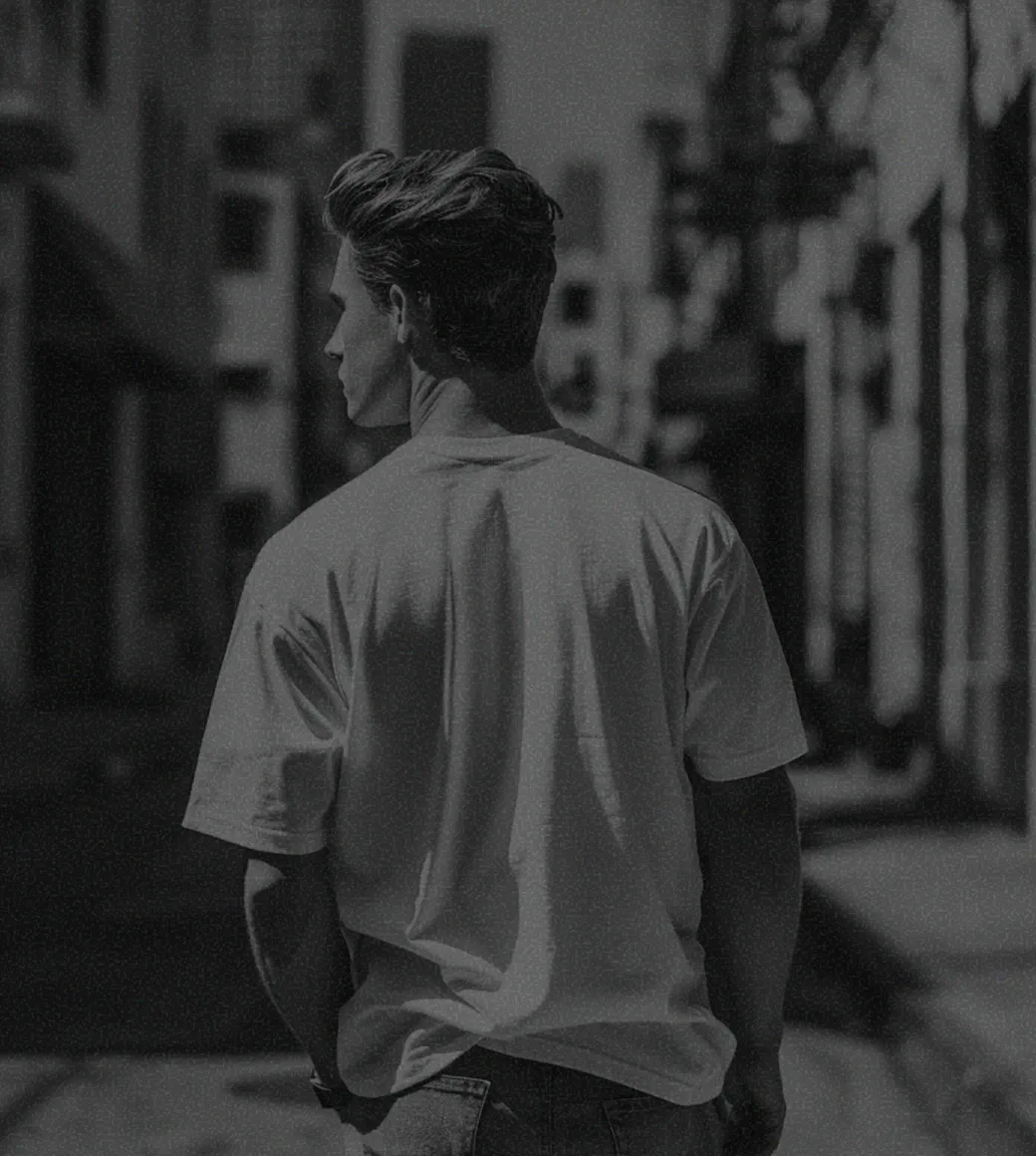 A man walking down a street next to tall buildings.