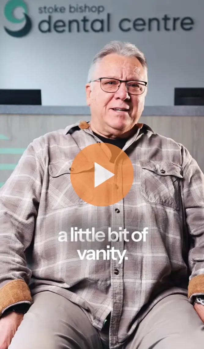 Older man in glasses and plaid shirt sitting in dental centre with text 'a little bit of vanity.'