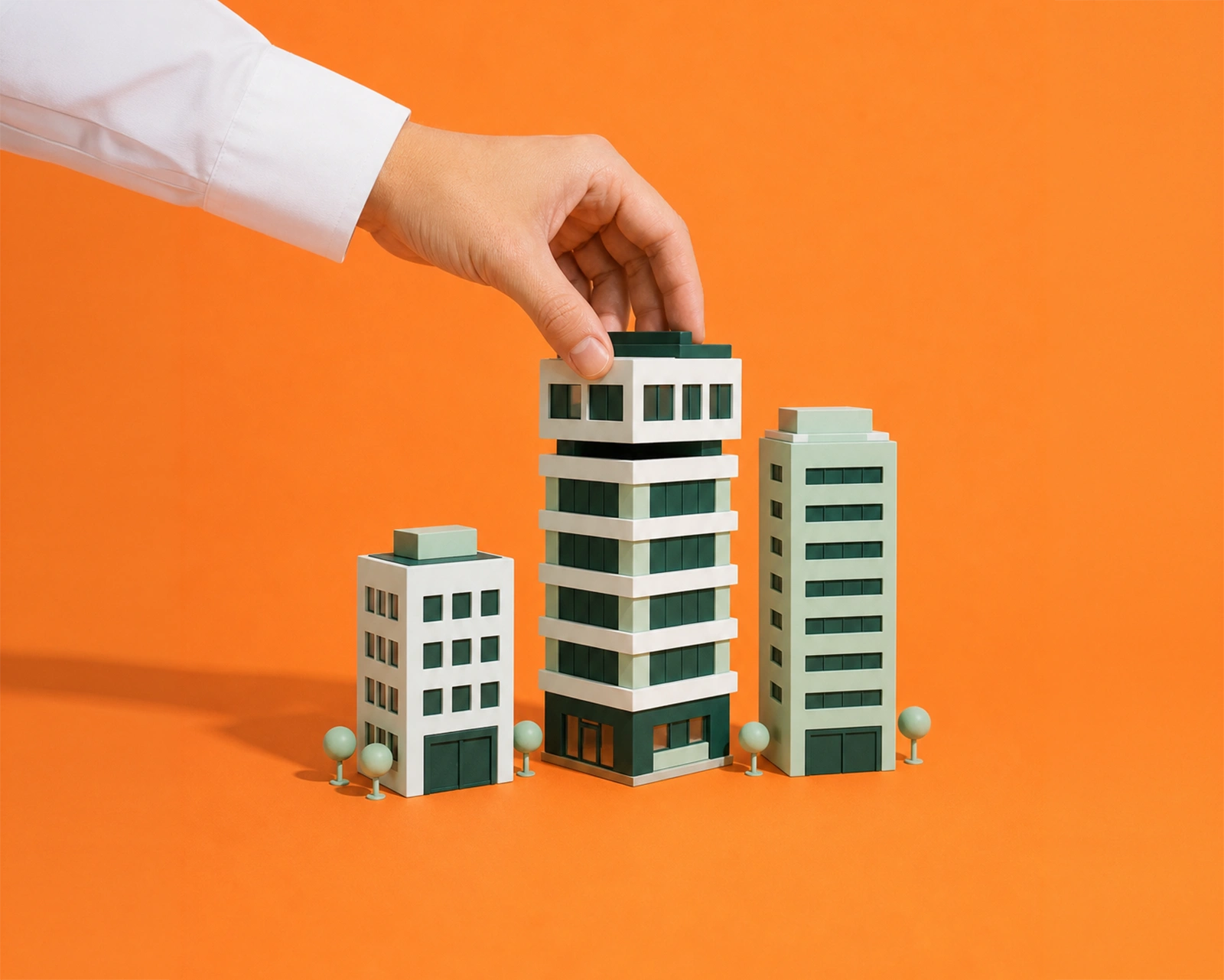 Hand placing a top block onto a toy commercial building model, illustrating commercial property purchase and refinancing options