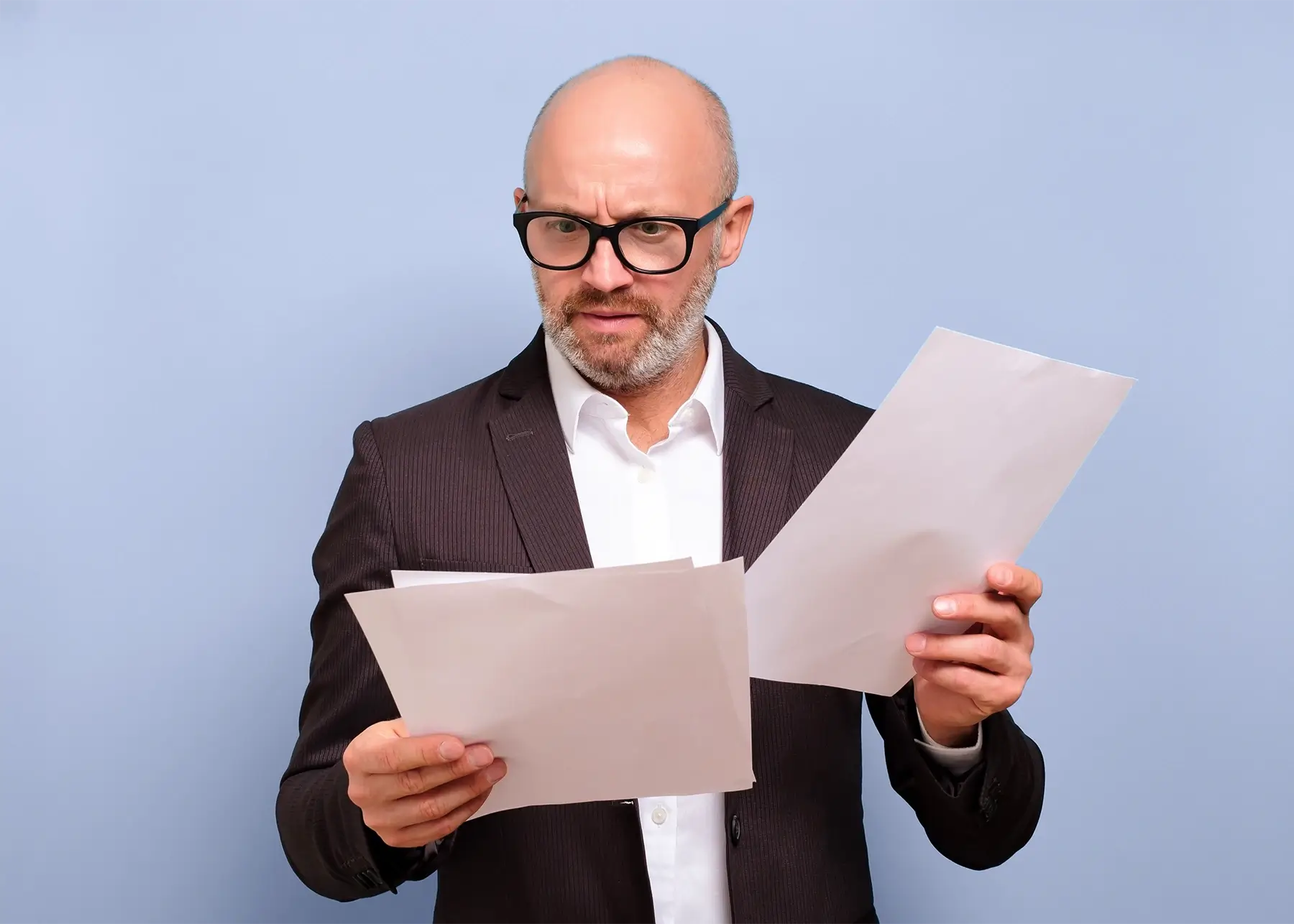 Man in suit examining complex financial statements, illustrating common challenges with bank loan approvals
